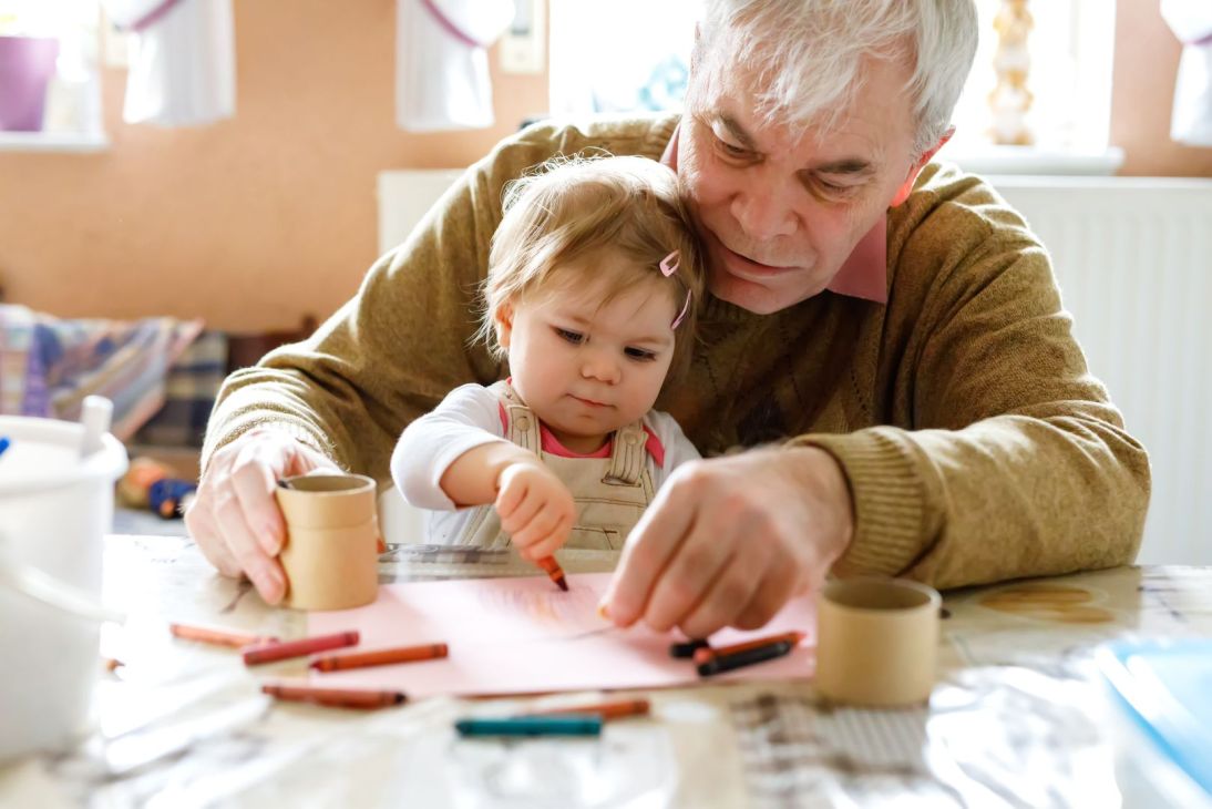 Senior man coloring with young child.