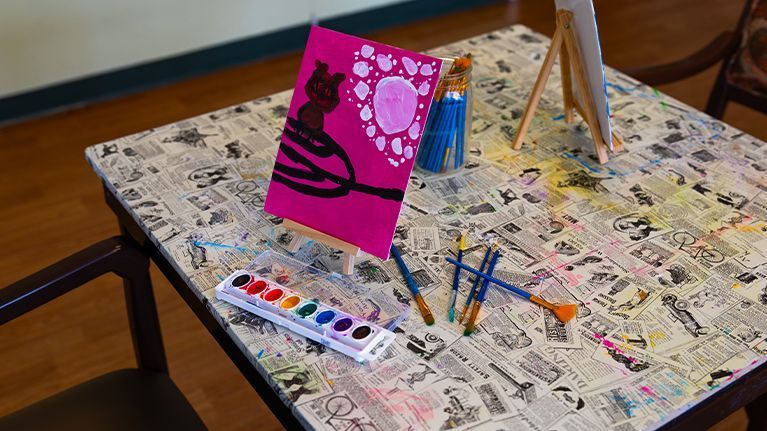 Art work on easel with paints and paint brushes 